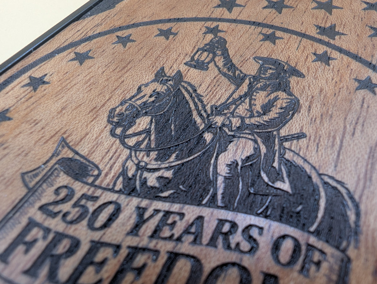 Wooden phone case with engraved image of Paul Revere on a horse and text '250 Years of Freedom'.